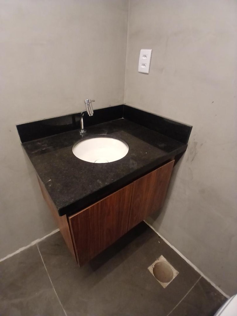 Bancada de granito com lavatório e gabinete em banheiro