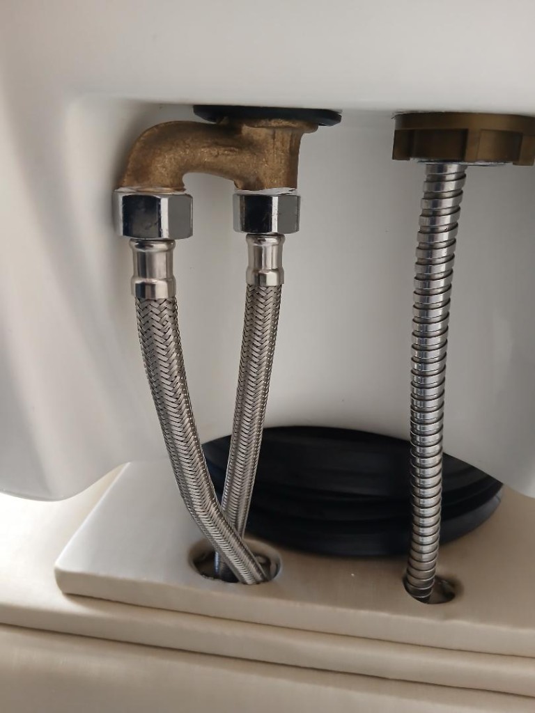 Mangotes flexíveis e conexões metálicas sob louça sanitária